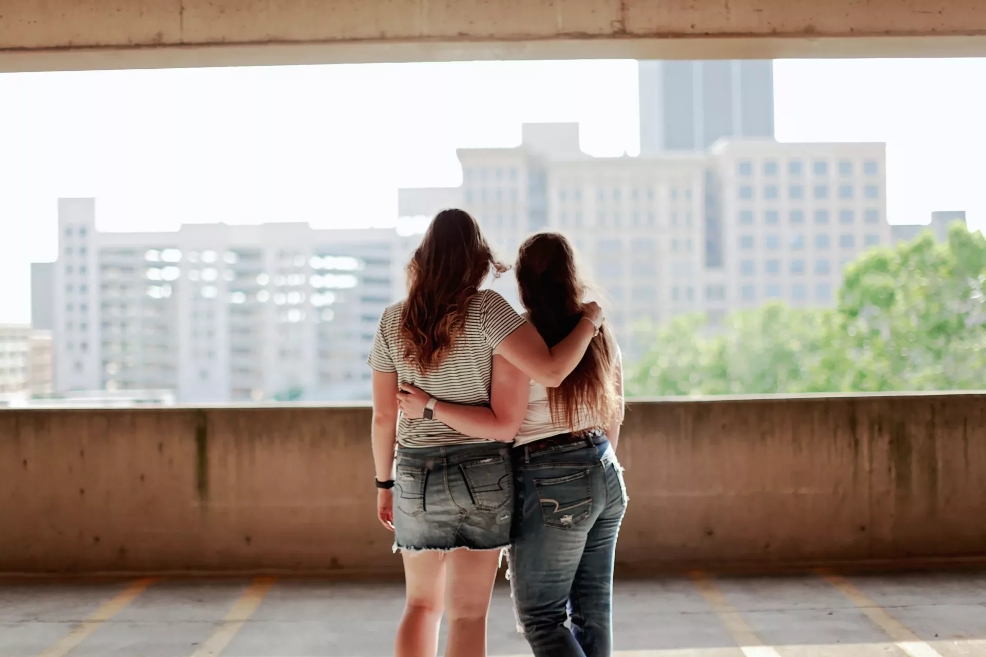 Two women hugging each other while looking at the city
