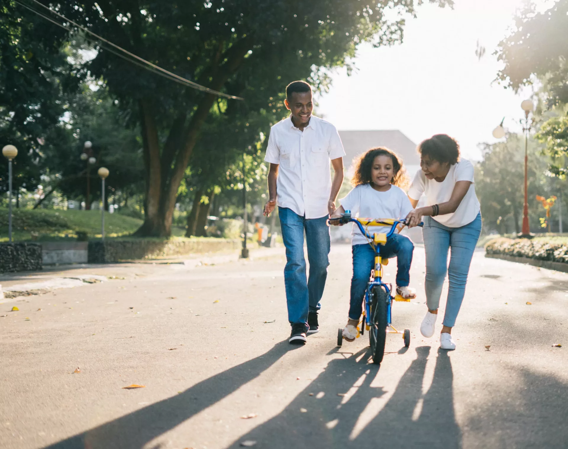 Happy family helping their kid ride a bike