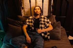 lonely man drinking alcohol while lying on bed